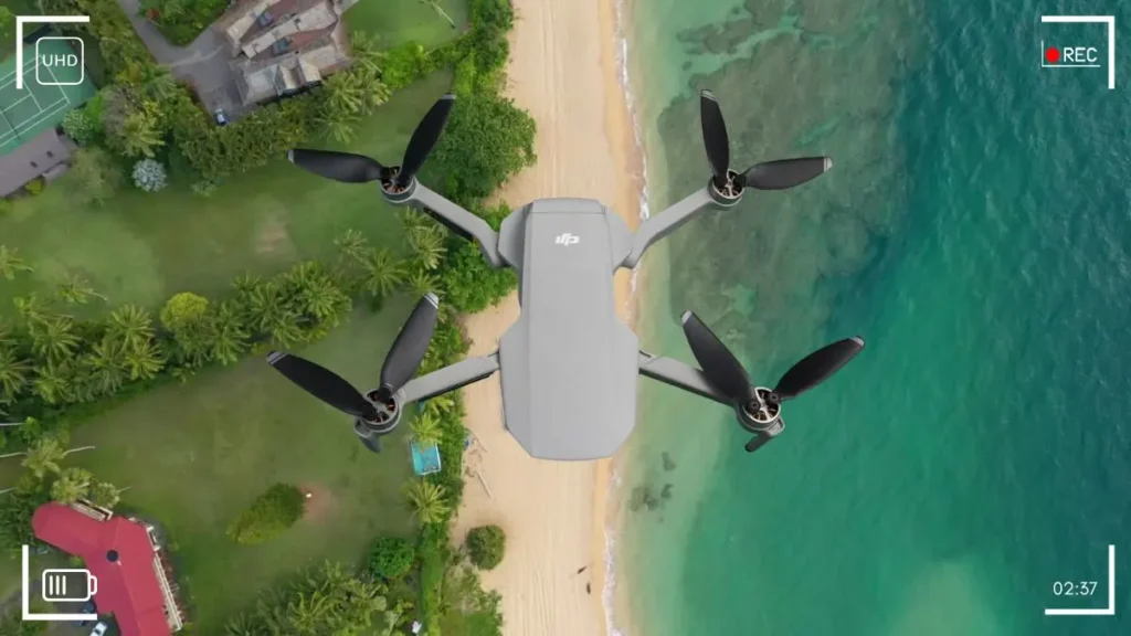 DJI Mini 2 drone flying above a turquoise green sandy beach, capturing stunning footage for Tool Tested review.