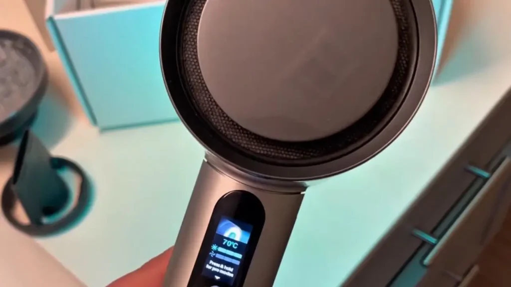 A person holding the AirLight Pro hair dryer, showing the digital screen with temperature and speed settings.