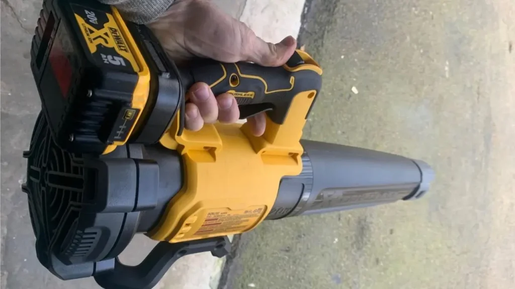 A hand holding the DEWALT DCBL722B blower with a DEWALT 20V MAX 5Ah battery attached, showing the battery connection and tool's design for Smart AI Gears.