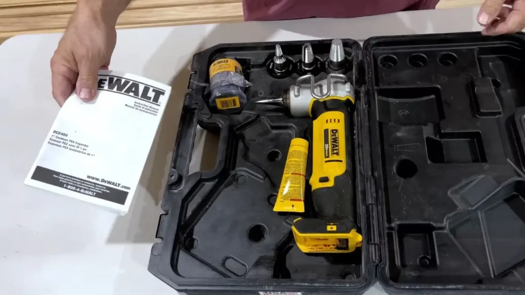 The DEWALT PEX Expander DCE400D2 kit box is open, showing the tool, battery, charger, and various expansion heads inside, along with the user manual.