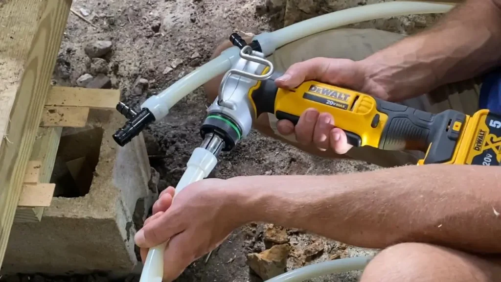 A plumber uses the DEWALT PEX Expander DCE400D2 to make a PEX pipe connection under a wooden floor, showing actual work in progress.