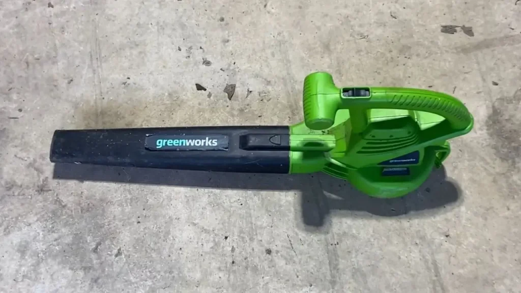 Close-up of Greenworks 24012 electric leaf blower in bright green and black, showing its design on a concrete surface. Smart AI Gears.