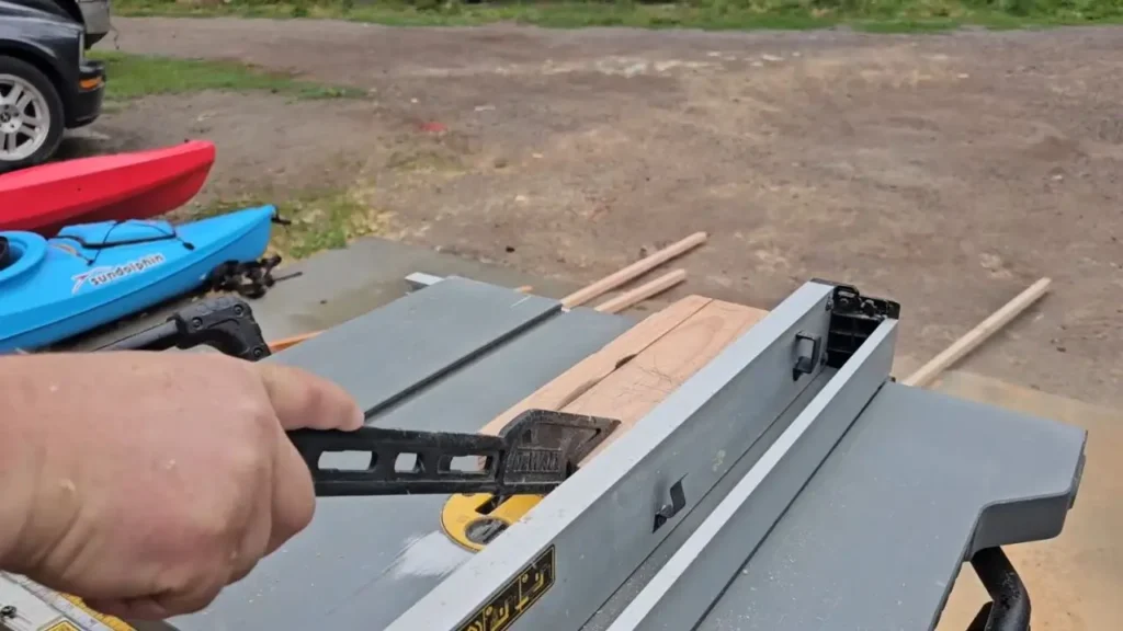 A person's hand guiding a piece of wood through the DeWalt DWE7491RS table saw
