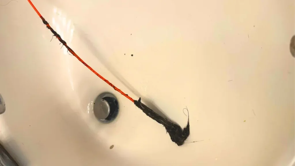 A Drain Weasel wand covered in a dense clump of hair, successfully extracted from a sink or drain. This demonstrates the tool's ability to remove blockages.
