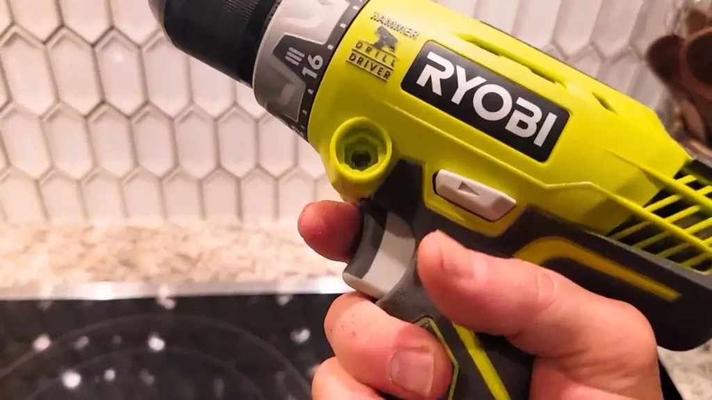 A person's hand holding a bright green and black drill, with a clear view of the 'Hammer' and 'Drill Driver' mode selector and clutch settings (up to 16). Shows a natural grip on the tool.