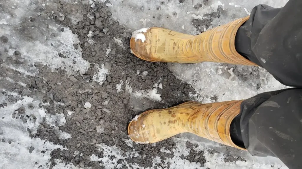Top-down view of Cofra Thermic steel toe boots on a job site with ice and slush, demonstrating cold weather performance.