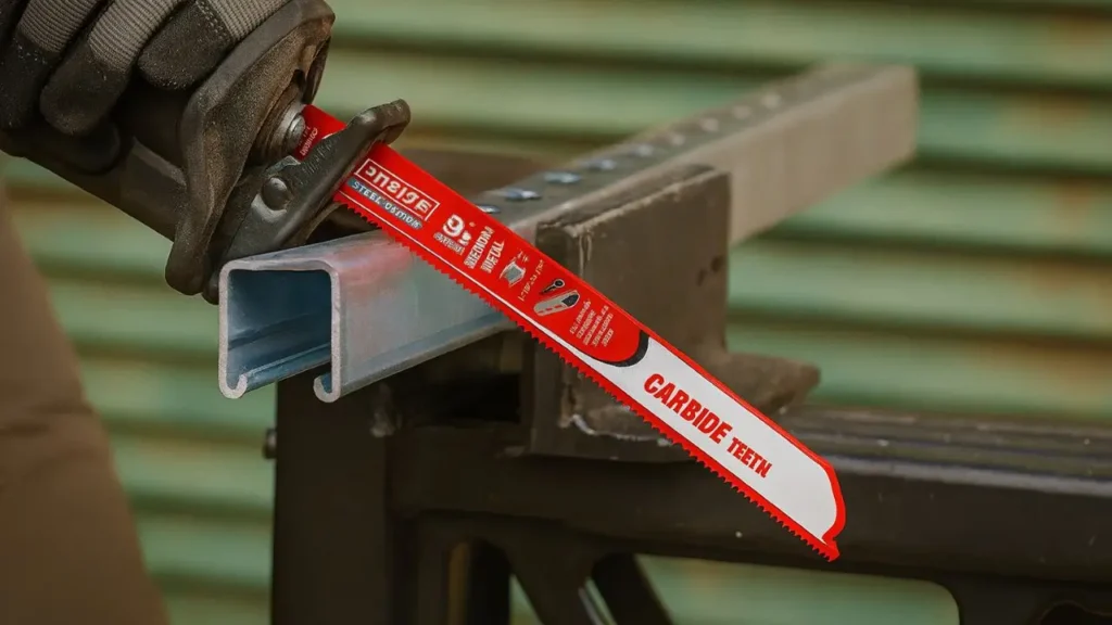 Close-up of a used Diablo Steel Demon carbide Sawzall blade on a workbench, with cut metal in background.