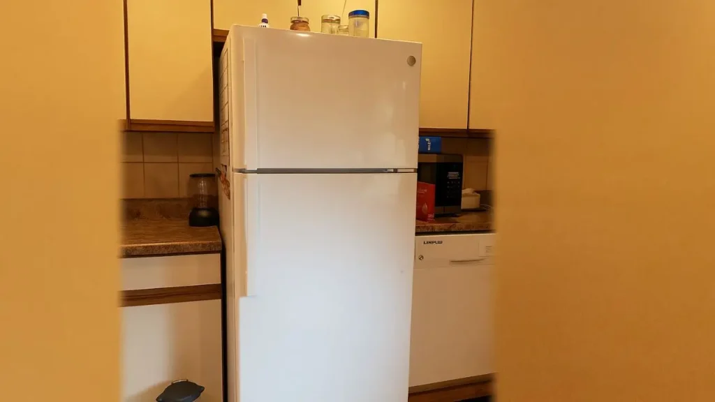 A side-angle view showing how the 28-inch General Electric GTS18HGNRWW refrigerator fits into a standard kitchen layout.