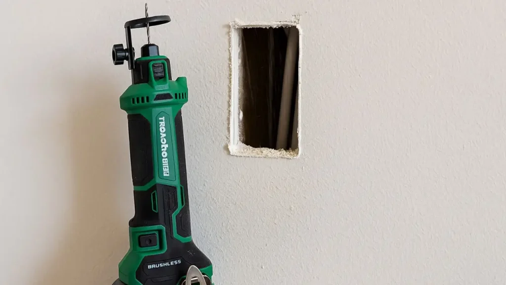 Metabo HPT Drywall Cut Out Tool M18DYAQ4 positioned beside a cleanly cut rectangular opening in a drywall wall, showcasing its effectiveness.