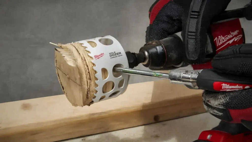 A Milwaukee Hole Dozer hole saw mounted on a Milwaukee Fuel cordless drill cutting through a piece of pine wood, with focused precision.