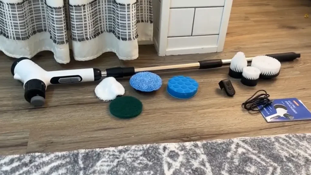 The electric spin scrubber with cleaning pads and other accessories arranged for first-time use.