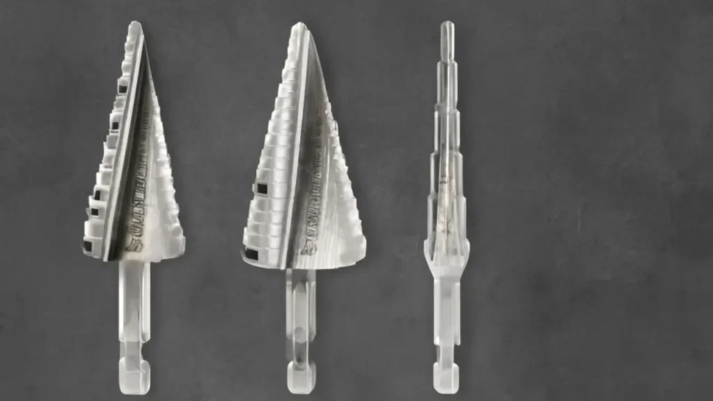 Three Spyder step drill bits with a polished silver finish, featuring conical shapes and a hexagonal shank, arranged neatly against a dark gray background.