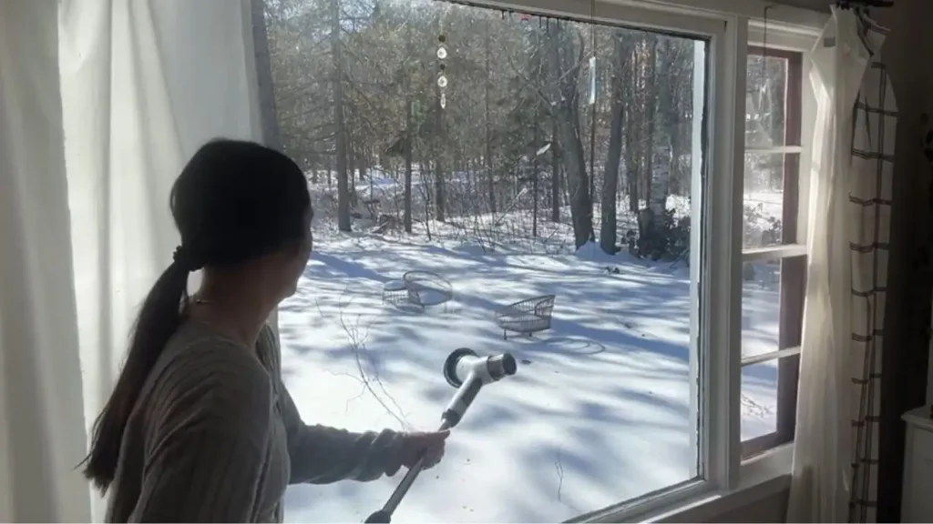 A person using the electric spin scrubber outside on a snowy day, showing its versatility for outdoor cleaning.