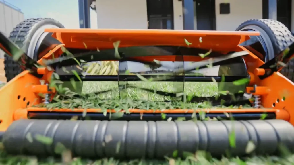 A close-up view of the LawnMaster's spinning blades, showing cut grass flying out.