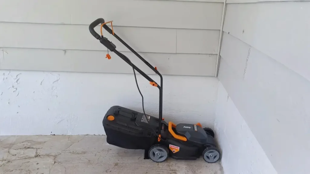 A cordless lawn mower stored upright against a wall.