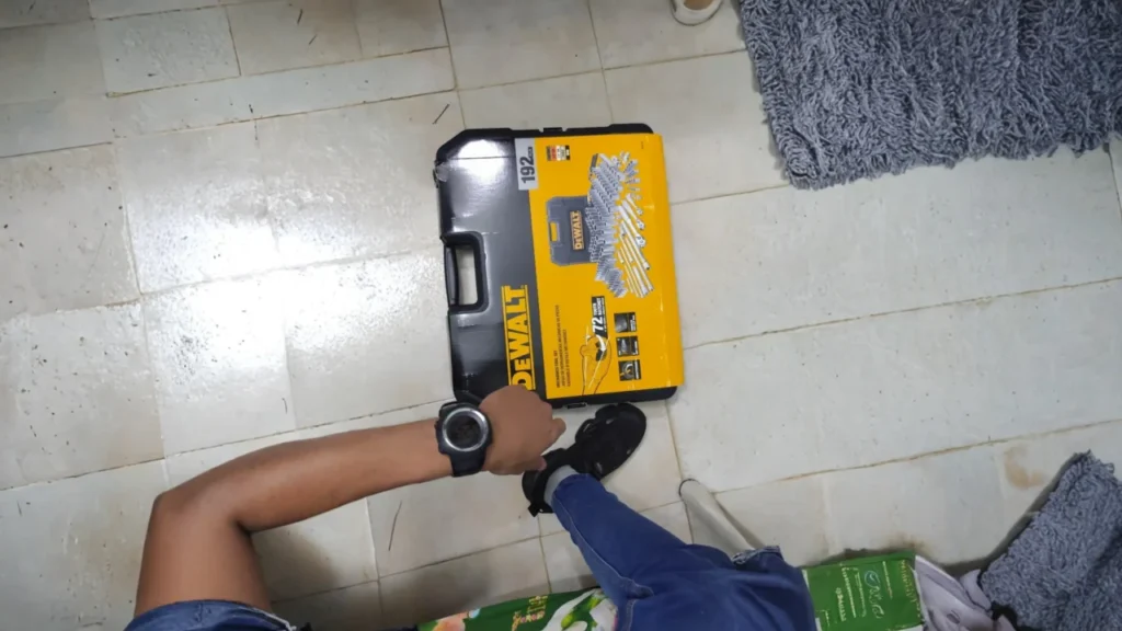 A person holding the DEWALT 192-piece tool set case on the floor, showing its compact and durable design.