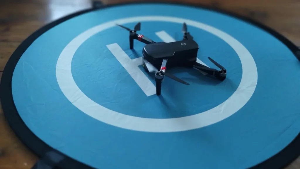 A drone is resting on the center of the blue KINBON landing pad, ready for takeoff or after a safe landing.