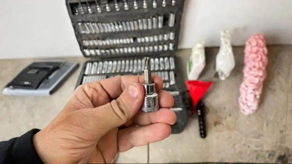 A person’s hand holding a hex bit socket from the tool set, highlighting one of the many specialized tools included.
