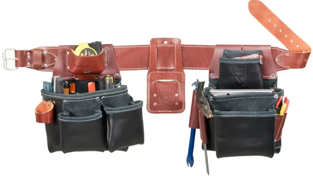A high-quality brown leather tool belt with dark gray pouches, designed for framing. The belt has a wide back for comfort and is equipped with multiple pockets holding tools like a hammer, tape measure, and various hand tools.