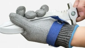A close-up of a hand wearing a chainmail-style metal work glove being tested against a sharp blade on Smart AI Gears.