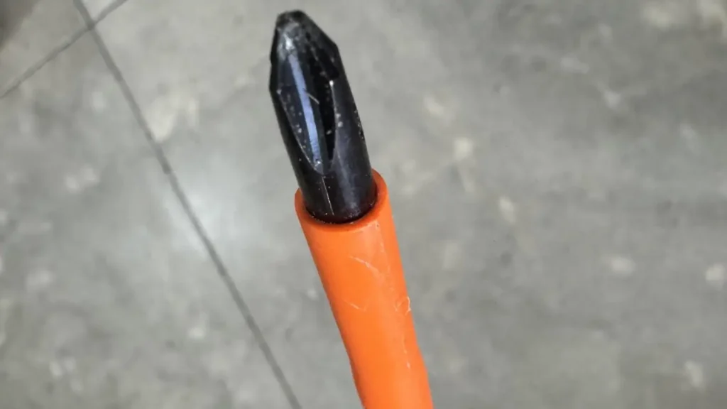Close-up of a Klein insulated screwdriver's slim tip, with orange insulation reaching close to the end.