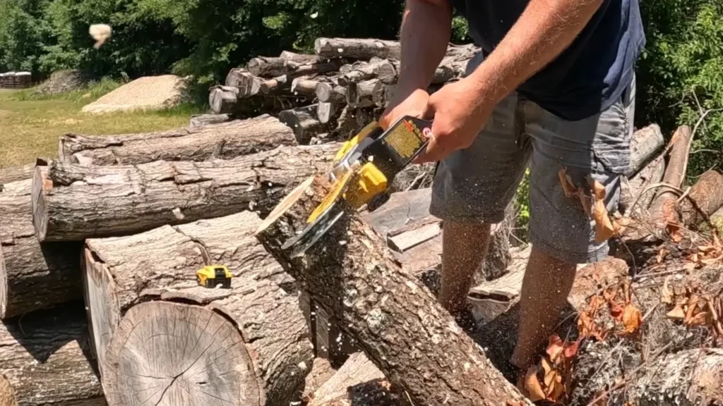 A person using a DEWALT 20V chainsaw to cut through a log.