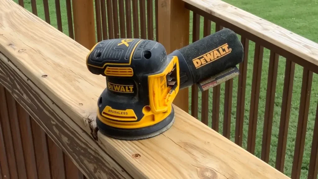 A DEWALT DCW210B cordless sander sitting on a wooden deck rail, Smart AI Gears