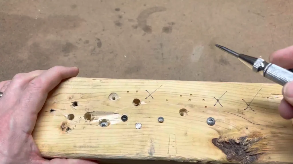 A piece of wood with several consistent and clear dimples, showing the accuracy of the automatic center punch.