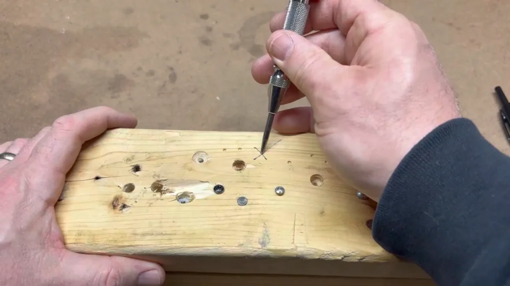 The tip of the NEIKO 02638A center punch is pressed down on a wooden surface, ready to make a mark.