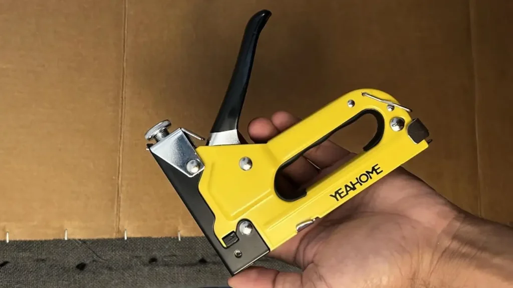 A hand holding the YEAHOME 4-in-1 staple gun, showing its ergonomic design.