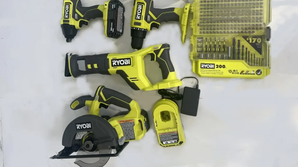 A user photo showing the RYOBI P1819 tools, batteries, and charger laid out on a marble floor, with a large 200-piece accessory kit shown (Note: Accessory kit may not be included in all standard P1819 packages).
