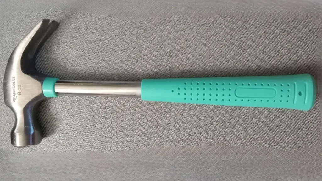 A close-up view of the Amazon Basics 8 oz claw hammer in turquoise, featuring its steel shaft and no-slip shock reduction grip.