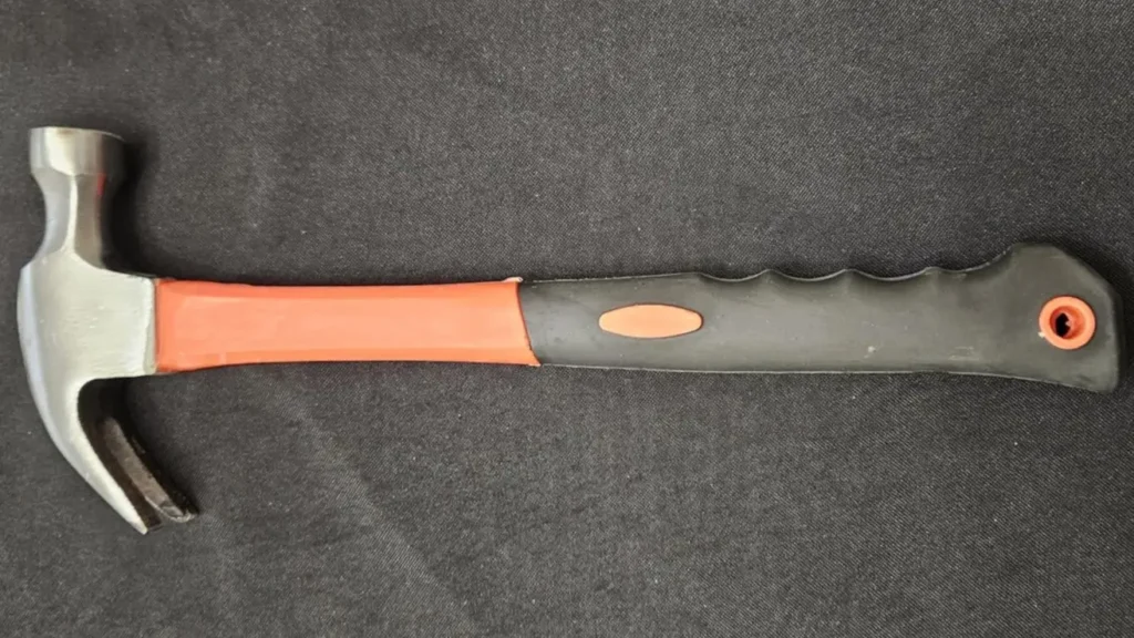 A top-down view of the DkOvn 8oz rip resting on a dark fabric, showing its high-carbon steel head and orange and black rubberized handle.