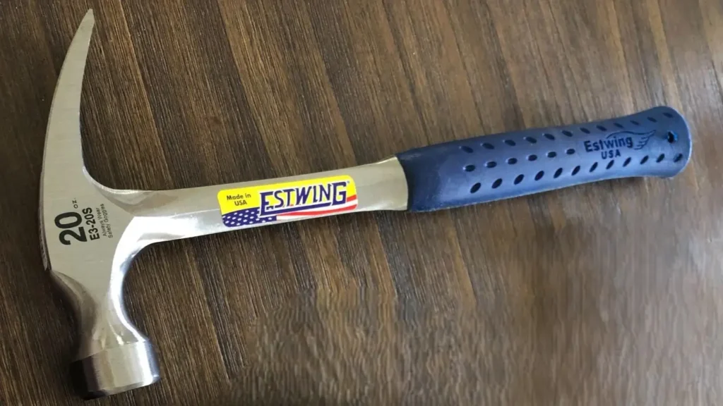 Top-down view of a solid steel Estwing straight rip with a blue nylon-vinyl grip, resting on a wooden surface.