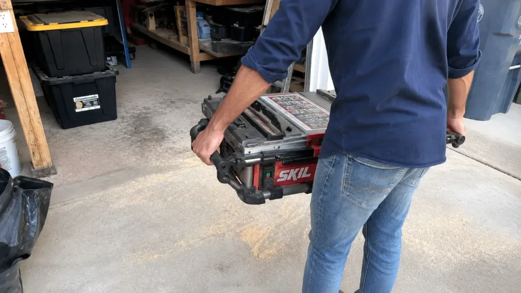 Carrying the folded portable table saw using the built-in side handles.