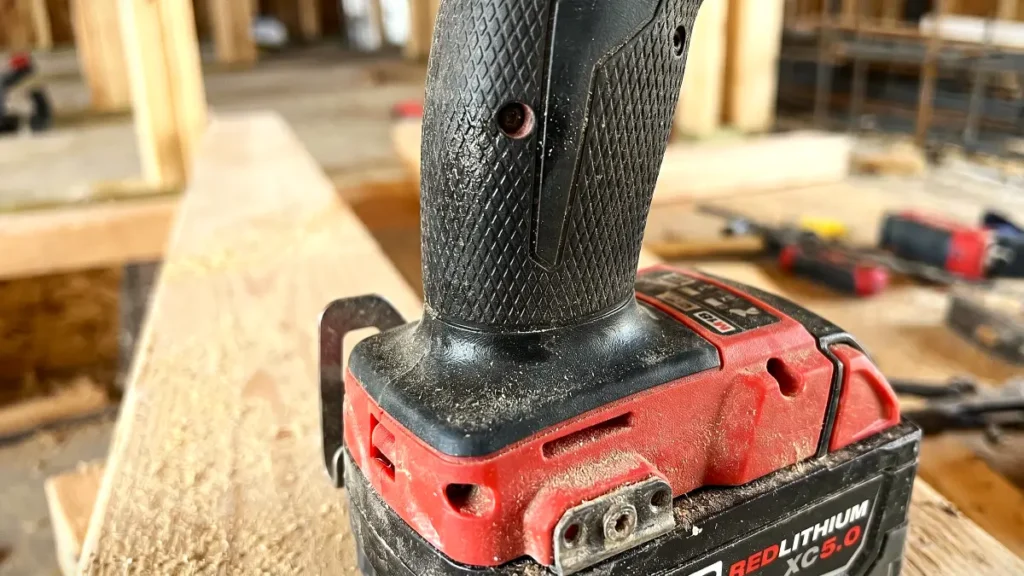 Close up of an impact driver rubber grip and battery base covered in light dust.