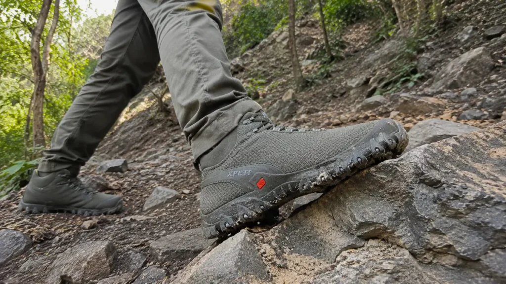 Close up of hiking boot soles gripping a steep rocky surface on a trail.
