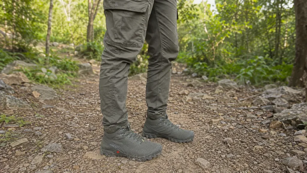 Dusty hiking boots standing on a loose gravel and dirt path.
