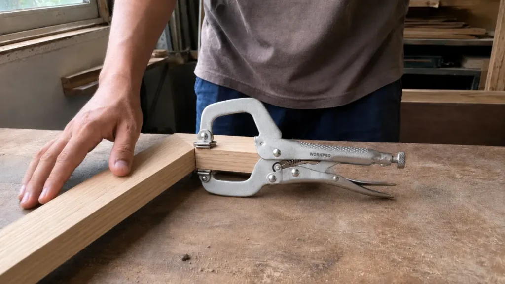 Hand tool holding a wooden picture frame joint together tightly during assembly.