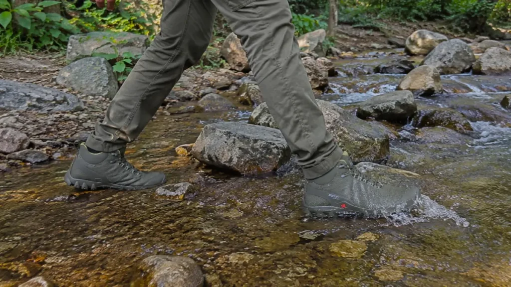 Hiking boots submerged in a shallow forest stream to test water resistance.