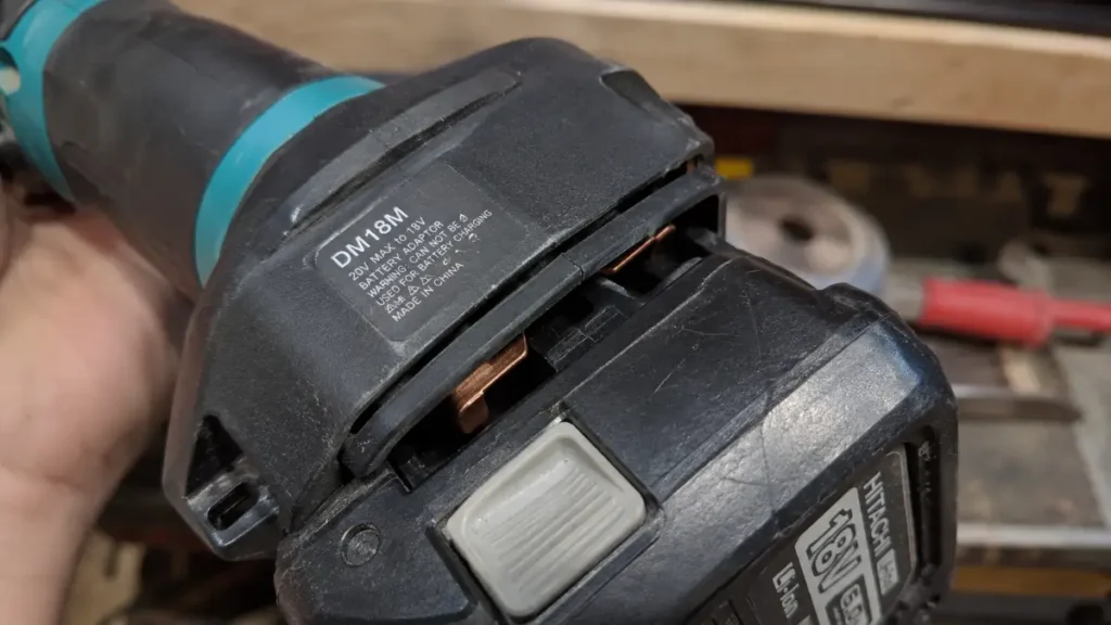 A third-party plastic power tool battery adapter connected to a cordless tool, highlighting potential safety and contact risks.